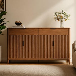 May include: A rectangular wooden sideboard featuring two top drawers and two lower cabinet doors with a vertical slatted texture. The piece has a warm brown finish, slim black metal handles, and stands on four tapered legs. It is a functional storage unit.
