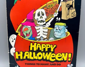 May include: A rectangular book cover with a black background featuring a large orange pumpkin. Inside the pumpkin are a skeleton, a witch, a blue monster, and an owl. The text reads Happy Halloween! Things to Make and Do.