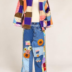May include: A long-sleeve jacket and jeans set. The jacket features a multi-colored patchwork design with various fabric patterns. The blue denim jeans are decorated with multiple fabric patches, including floral appliques and sunflowers.