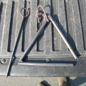 May include: A metal triangle and a metal rod with a ring on the end. The items are lying on a black surface.