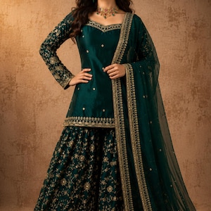 Op de afbeelding: Een donker smaragdgroene sharara-set bestaande uit een tuniek met lange mouwen, een vierkante halslijn en gouden borduursels. De uitlopende broek en de transparante dupatta zijn versierd met gouden bloemmotieven. De tekst SAANJH is zichtbaar.