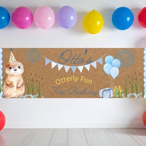 Peut inclure: Une bannière rectangulaire sur fond papier kraft brun avec une loutre dessinée portant un chapeau de fête, des fanions bleus et le texte Otto's Otterly Fun First Birthday. Le motif inclut des ballons bleus, des cadeaux et des roseaux.