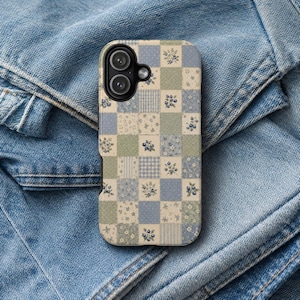 May include: A rectangular smartphone case featuring a patchwork design of alternating squares in shades of sage green, dusty blue, and cream. The pattern includes floral motifs, small polka dots, and gingham checks with a black camera lens cutout.