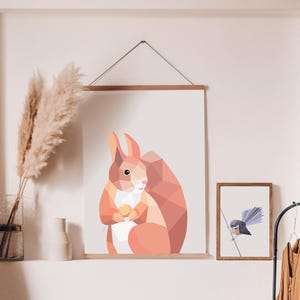 Puede incluir: Una impresión geométrica de una ardilla roja sosteniendo una nuez, enmarcada en un marco de madera y colgada en una pared blanca.