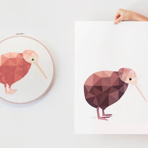 May include: A geometric illustration of a kiwi bird in shades of pink and brown. The image is printed on white paper and framed in a white frame.