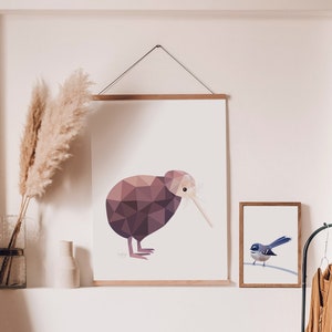 Peut inclure: Illustration g&eacute;om&eacute;trique d'un kiwi aux tons bruns et violets, accroch&eacute;e au mur. Une petite impression encadr&eacute;e d'un oiseau bleu est &agrave; c&ocirc;t&eacute;. De l'herbe de la pampa d&eacute;corative dans un vase est &eacute;galement visible.