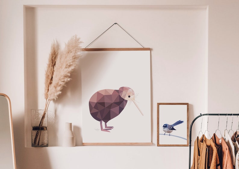 Peut inclure: Illustration g&eacute;om&eacute;trique d'un kiwi aux tons bruns et violets, accroch&eacute;e au mur. Une petite impression encadr&eacute;e d'un oiseau bleu est &agrave; c&ocirc;t&eacute;. De l'herbe de la pampa d&eacute;corative dans un vase est &eacute;galement visible.