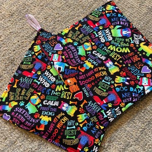 May include: Two black fabric squares with colourful dog-themed prints. The fabric features phrases like "My Dog is My Life", "Dogs are the Best", "Keep Calm Feed the Dog", and "I Just Love My Dog".