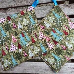 May include: Two green, red, and blue Christmas tree patterned pot holders with blue ribbon ties.