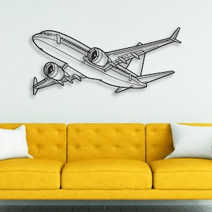 May include: A black metal wall art piece shaped like a commercial aeroplane in flight. The design features a clean, minimalist outline of a jet with two prominent engines mounted under the wings, captured in a side-profile view angled upward.