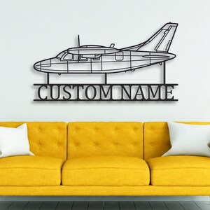 May include: A black metal wall art piece featuring a side profile silhouette of a propeller airplane. Below the aircraft, a horizontal bar displays the text CUSTOM NAME in a bold, sans-serif font, connected to the plane by two vertical supports.