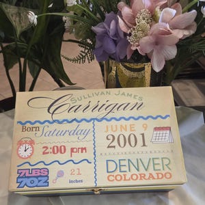 May include: A rectangular wooden keepsake box featuring a cream-coloured lid with printed birth details for Sullivan James Carrigan, born Saturday, 9 June 2001, at 2:00 pm in Denver, Colorado, weighing 7 lbs 7 oz and measuring 53.34 cm long.
