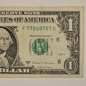 May include: A United States one-dollar bill featuring a portrait of George Washington on the left. The note displays the text Federal Reserve Note, The United States of America, Washington D.C., Series 2017 A, and the signature of Steven T. Mnuchin.
