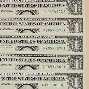 May include: A stack of five sequential one-dollar bills featuring the text Federal Reserve Note and United States of America. The serial numbers G 28574568 F through G 28574572 F are printed in green ink on the right side of each paper currency note.