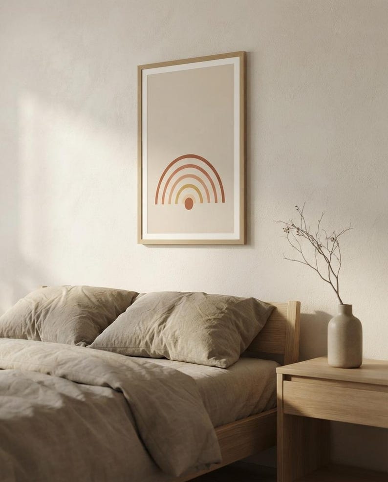 May include: A framed vertical wall art print featuring a minimalist rainbow graphic with concentric arches in shades of terracotta, orange, and yellow, centered above a small solid circle on a light beige background, enclosed in a light wood frame.