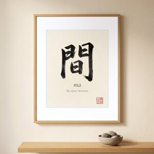 Framed "Ma" calligraphy artwork in a bright neutral living room featuring clean, modern minimalist decor.