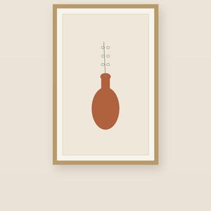 May include: A framed wall art print featuring a solid terracotta-colored oval vase with a thin, vertical line extending upward from the neck, decorated with three small, light-colored circular shapes arranged symmetrically along the stem.