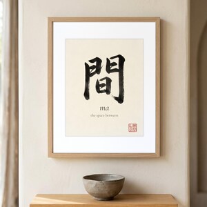 Framed "Ma" calligraphy artwork in a bright neutral living room featuring clean, modern minimalist decor.