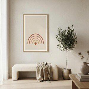 May include: A framed rectangular wall art print featuring a series of concentric semicircular arches in shades of terracotta, rust, and muted yellow, centered above a small solid circle on a light beige background within a thin wooden frame.