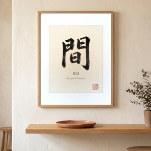 Framed "Ma" calligraphy artwork in a bright neutral living room featuring clean, modern minimalist decor.