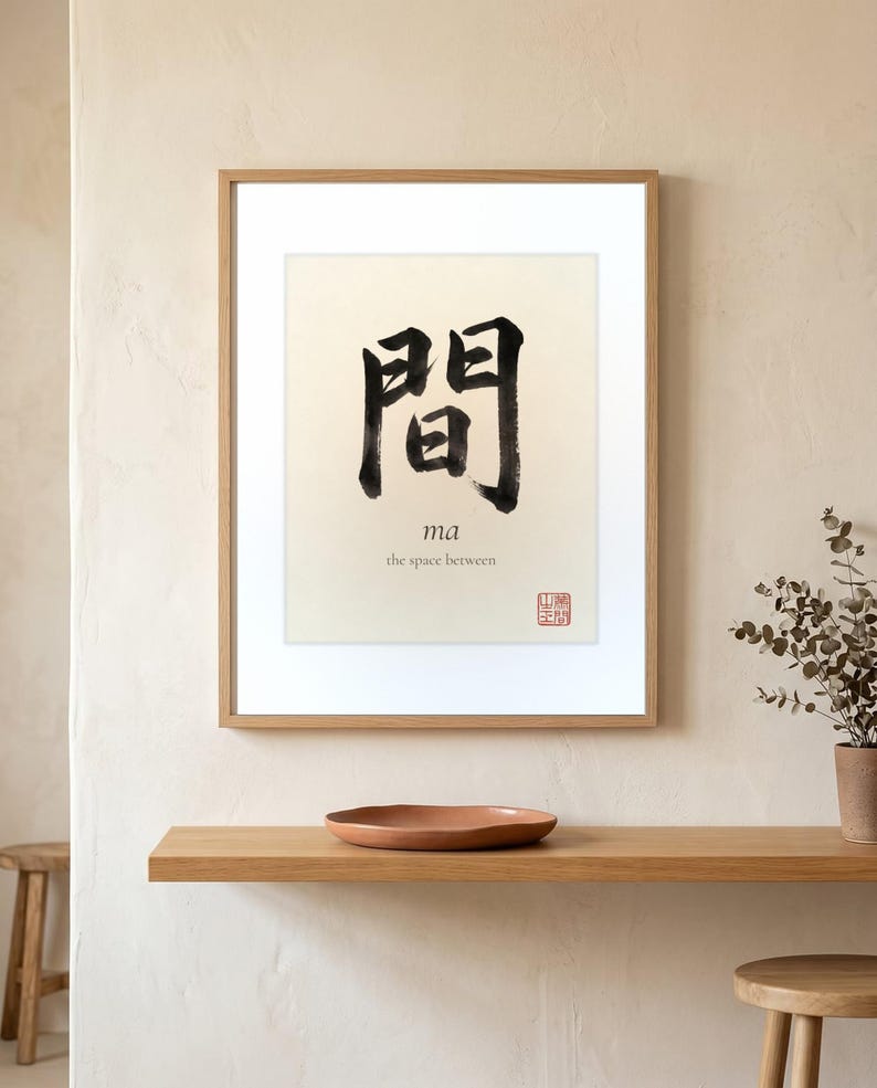 Framed "Ma" calligraphy artwork in a bright neutral living room featuring clean, modern minimalist decor.