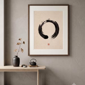 Framed Sumi Enso print displayed above a modern console table in a Japandi-inspired living room with neutral decor.