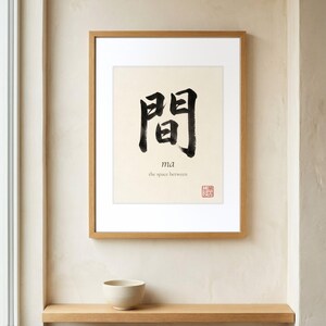 Framed "Ma" calligraphy artwork in a bright neutral living room featuring clean, modern minimalist decor.