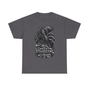 May include: A dark gray short-sleeve t-shirt featuring a black and white graphic of a multi-tailed fox standing on a rock. The text below the fox reads BORN TO BE A PROBLEM NOT A FOLLOWER in a stylized, distressed white font with sharp edges.