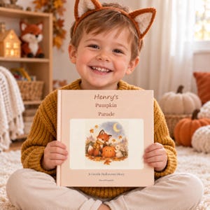 Smiling toddler sitting with his personalised Halloween storybook – custom name pumpkin story and toddler Halloween gift