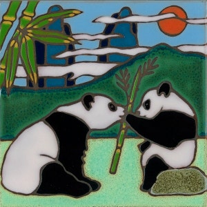 May include: Two black and white panda bears sitting on a green grassy surface with a bamboo stalk between them. The background features a blue and white sky with clouds and a red sun.