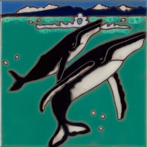 May include: Two black and white whales leap out of the turquoise water. The whales are silhouetted against a blue sky with white clouds.