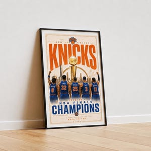 Pode incluir: Um cartaz vertical emoldurado dos New York Knicks com o texto "NEW YORK KNICKS", "NBA FINALS CHAMPIONS" e "A NEW YORK LEGACY BACK ON TOP". O gr&aacute;fico mostra cinco jogadores de basquete com camisas azuis diante de um trof&eacute;u.