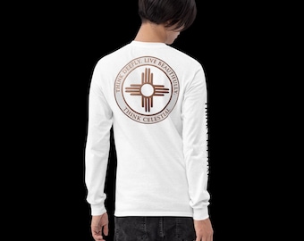 Puede incluir: Una camiseta blanca de manga larga con un gráfico circular en la espalda que muestra un símbolo solar Zia marrón y el texto "THINK DEEPLY. LIVE BEAUTIFULLY. THINK CELESTIAL." El texto "THINK CELESTIAL" aparece impreso verticalmente en la manga izquierda.