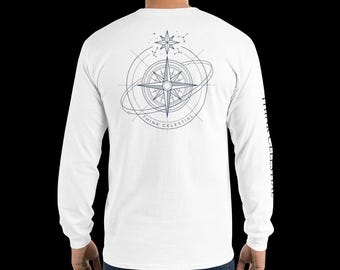 Puede incluir: Una camiseta blanca de manga larga con un gráfico azul oscuro en la espalda. El diseño muestra una rosa de los vientos rodeada de anillos orbitales y una estrella, con el texto "THINK CELESTIAL" impreso bajo la brújula y en la manga derecha.