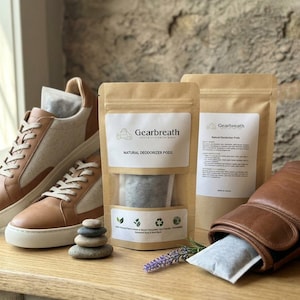 Peut inclure: Deux baskets beige et blanc, un gant de boxe en cuir marron et deux sachets en papier kraft marron étiquetés Gearbreath Natural Deodorizer Pods. Les sachets contiennent de petits sacs en tissu, dont un est visible dans une basket et un autre dans le gant.