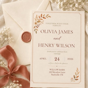 May include: A cream-colored wedding invitation card featuring brown text, watercolor botanical accents, and a double-line border. The card displays the names Olivia James and Henry Wilson, the date April 24, 2026, and the location Willow Barn, 123 Meadow Lane, Nashville TN.
