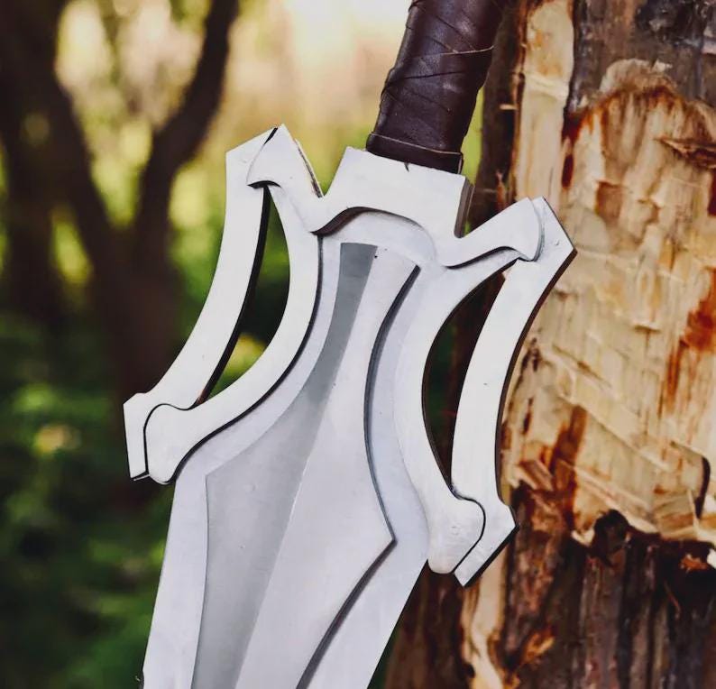 May include: A silver-colored sword with a wide, pointed blade and a complex, multi-layered guard featuring symmetrical cutouts. The handle is wrapped in dark brown leather, providing a textured grip for the hilt of this metallic weapon.