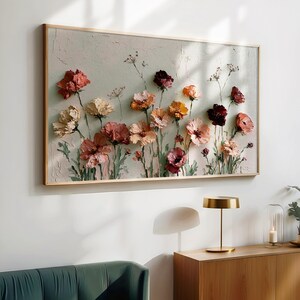 May include: A rectangular wall art piece featuring a textured impasto painting of various flowers in shades of red, pink, orange, and cream against a pale, neutral background. The artwork is enclosed in a thin, light-colored wooden frame.