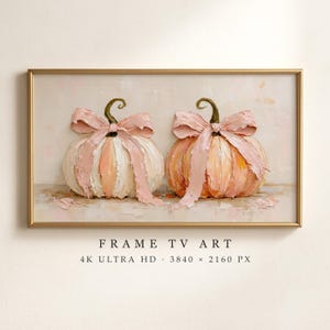 Puede incluir: Una obra de arte digital enmarcada rectangular que presenta dos calabazas texturizadas de estilo empaste en tonos rosa suave y crema. Cada calabaza está adornada con un gran lazo de cinta rosa a juego. El texto debajo dice: FRAME TV ART 4K ULTRA HD 3840 x 2160 PX.