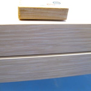 K&ouml;nnte beinhalten: Nahaufnahme einer hellen Holzkiste mit einem Stapel kleiner Holzbl&ouml;cke obenauf. Die Kiste hat ein helles Holzmaserungsmuster. Die Bl&ouml;cke haben farbenfrohe kreisf&ouml;rmige Designs.