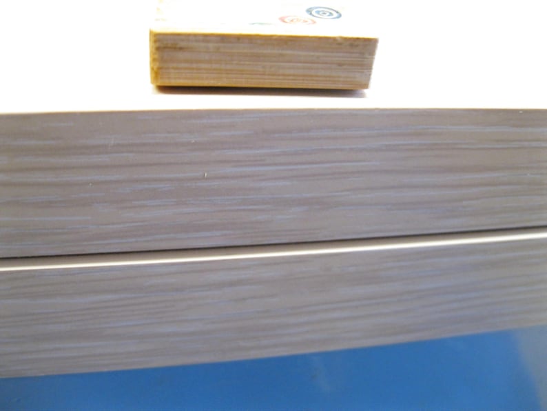 K&ouml;nnte beinhalten: Nahaufnahme einer hellen Holzkiste mit einem Stapel kleiner Holzbl&ouml;cke obenauf. Die Kiste hat ein helles Holzmaserungsmuster. Die Bl&ouml;cke haben farbenfrohe kreisf&ouml;rmige Designs.