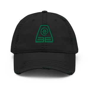 Peut inclure: Une casquette de baseball noire avec une finition usée et vieillie sur la visière et la calotte. Le panneau avant présente un motif brodé vert composé d'une spirale centrale dans une forme trapézoïdale au-dessus de deux barres.