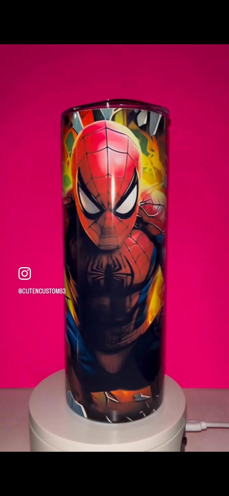 May include: A cylindrical tumbler featuring a vibrant, full-wrap graphic of the superhero Spider-Man in his iconic red and blue suit. The design includes yellow and orange flame-like accents, a black spider emblem on the chest, and a clear lid.