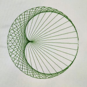 May include: A circular embroidery design stitched in dark green thread on a plain white fabric background. The pattern consists of straight lines radiating from a central point to form a geometric curve, creating a crescent-like shape.