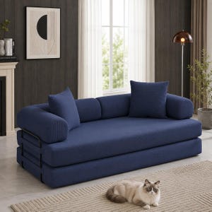 May include: A navy blue sofa bed featuring a thick, layered mattress design with a black metal frame. The piece includes two matching square throw pillows and two cylindrical bolster pillows, all upholstered in a textured navy blue fabric.