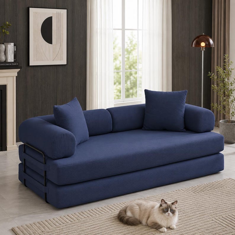 May include: A navy blue sofa bed featuring a thick, layered mattress design with a black metal frame. The piece includes two matching square throw pillows and two cylindrical bolster pillows, all upholstered in a textured navy blue fabric.