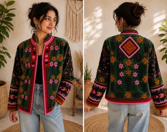 May include: A dark green velvet jacket featuring a mandarin collar and long sleeves. The jacket is decorated with vibrant floral embroidery in shades of pink, orange, and black, accented by geometric patterns and bright pink trim along the edges.