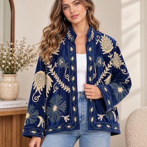 Könnte beinhalten: Eine tiefblaue Samtjacke mit offener Vorderseite, langen Ärmeln und Stehkragen. Das Kleidungsstück ist mit aufwendigen Blumen- und Paisley-Stickereien in Creme- und gedämpften Grüntönen verziert, die die Vorderteile und Ärmel bedecken.