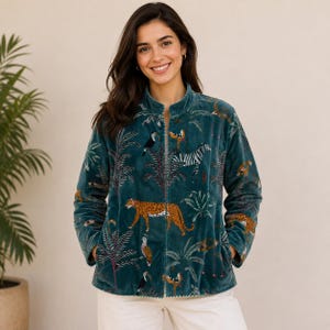Könnte beinhalten: Eine petrolfarbene Samtjacke mit einem lebendigen Dschungel-Print, der einen Leoparden, ein Zebra, Tukane und verschiedene tropische Pflanzen zeigt. Die Jacke hat einen Stehkragen, lange Ärmel, einen Reißverschluss vorne und seitliche Taschen.