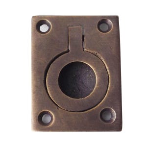 Puede incluir: Un tirador empotrado rectangular de bronce con un anillo circular central que se pliega plano en una depresión circular. El herraje tiene un acabado de pátina oscura envejecida e incluye cuatro orificios avellanados en las esquinas.